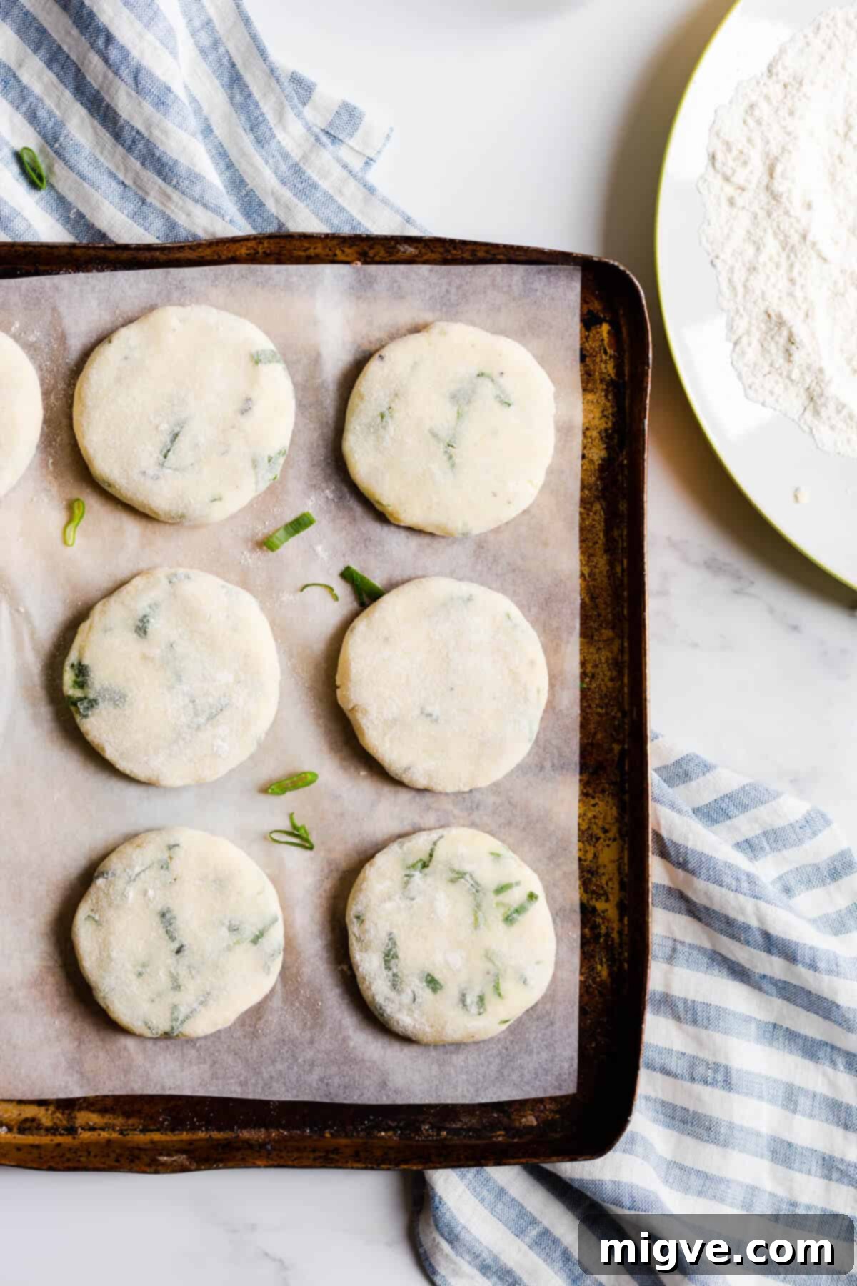 Top view of a baking tray neatly arranged with uncooked potato patties, lightly floured and ready for chilling or cooking.