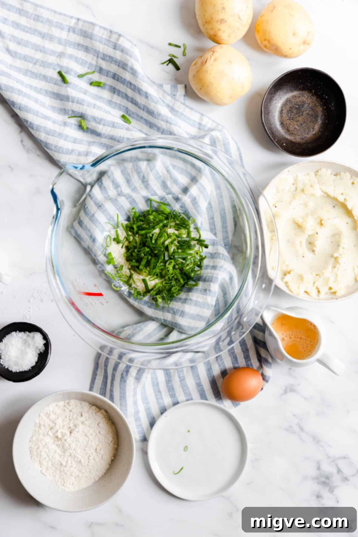 Overhead shot of a bowl containing grated Parmesan cheese and freshly chopped chives, a key flavor combination for the potato patties.