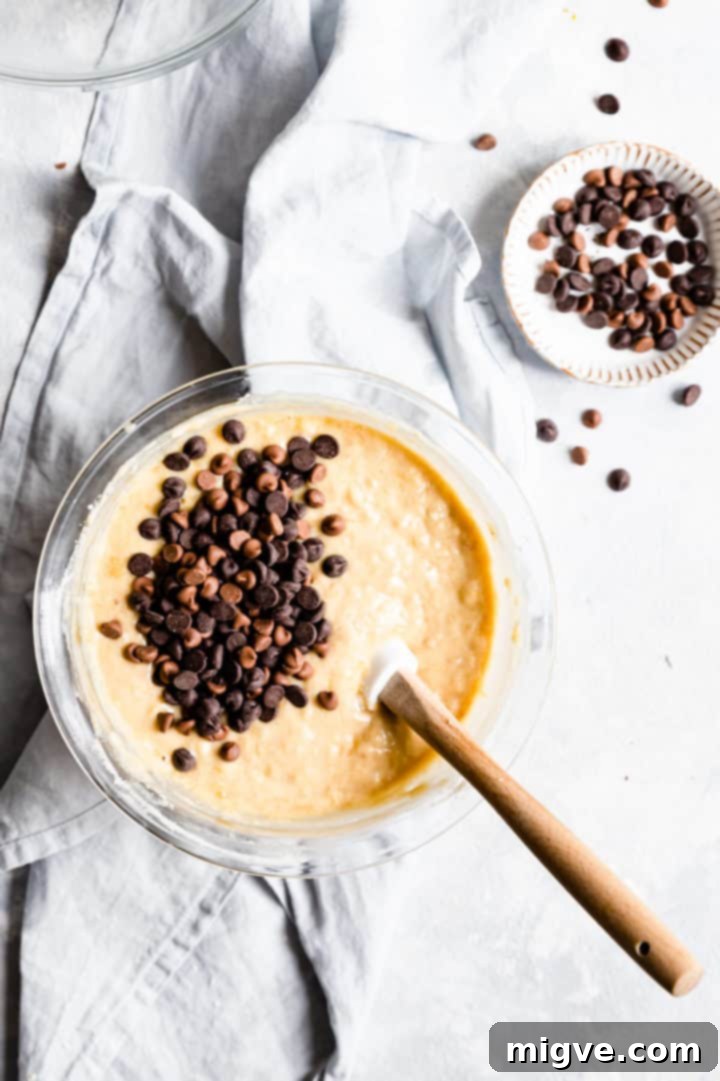 Top-down view of a bowl containing the finished banana bread batter, generously mixed with numerous chocolate chips, ready for baking.