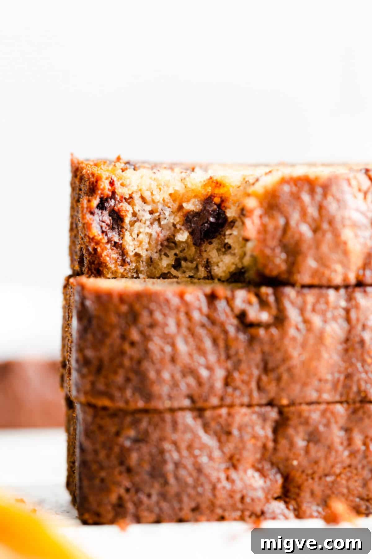 Super close-up of a bite taken out of a slice of moist chocolate chip banana bread, revealing its tender texture and perfectly melted chocolate pockets.