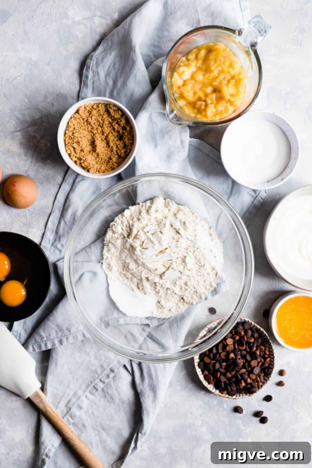 Top-down view of a large mixing bowl filled with dry ingredients: flour and baking soda, measured and ready.