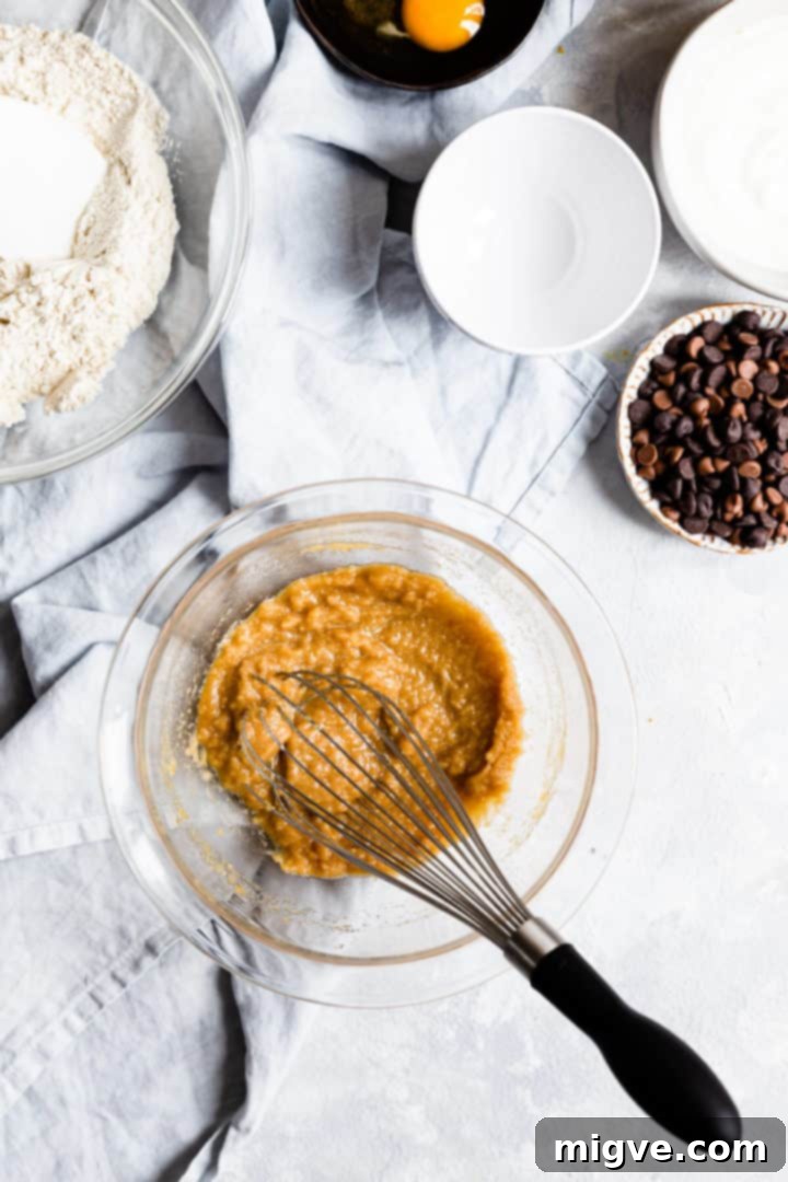 Overhead shot of melted butter and sugars whisked together into a smooth, creamy mixture in a bowl.