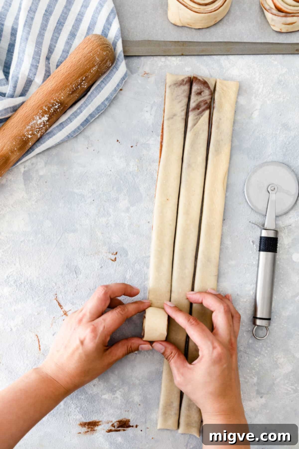top view of a person rolling strips of dough