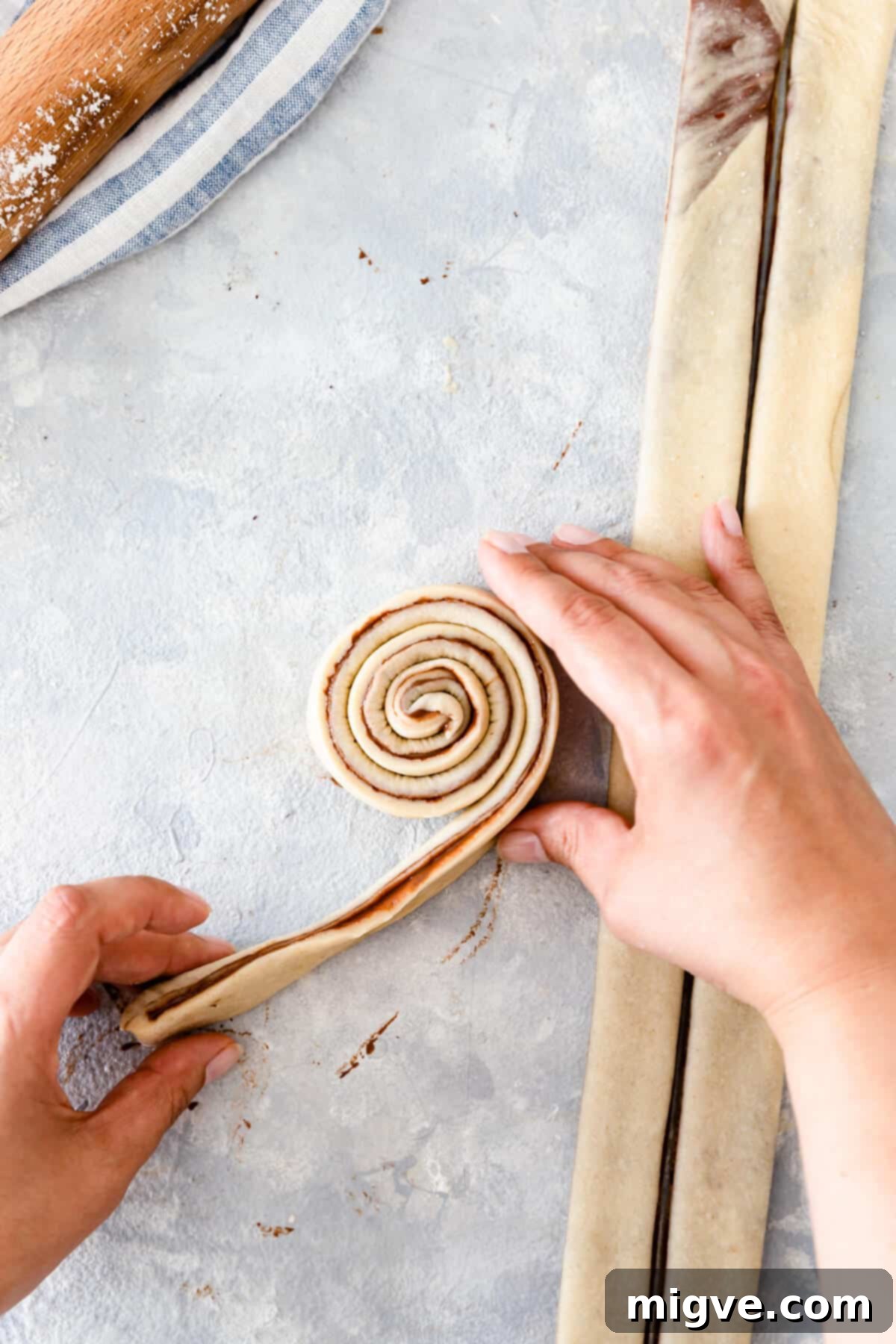 overhead shot of strip of dough being rolled into swirl