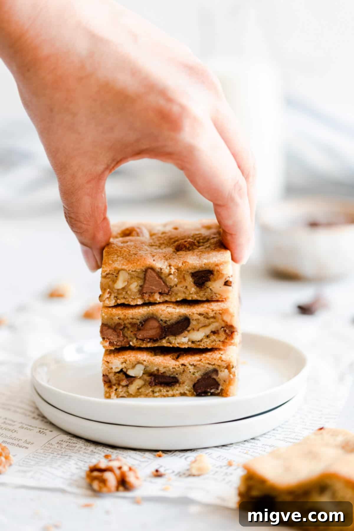 Chocolate Chip and Walnut Blondies 4 Close-up side view of a hand reaching for a delicious blondie bar, highlighting its soft texture