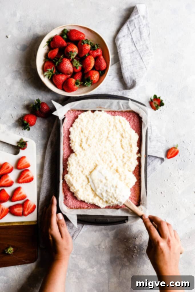 top view showing a person spreading coconut mixture into baking tin