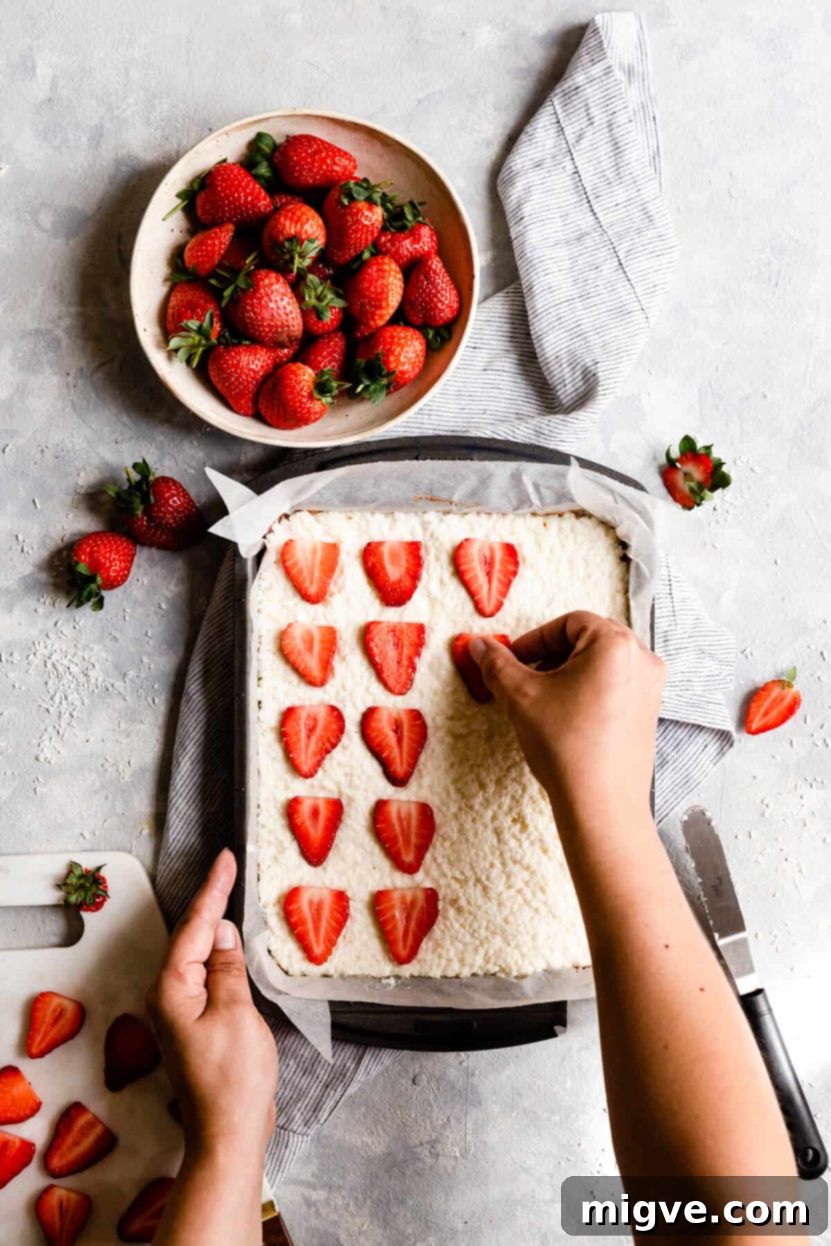 top view of strawberry slices being placed on top of the coconut bake
