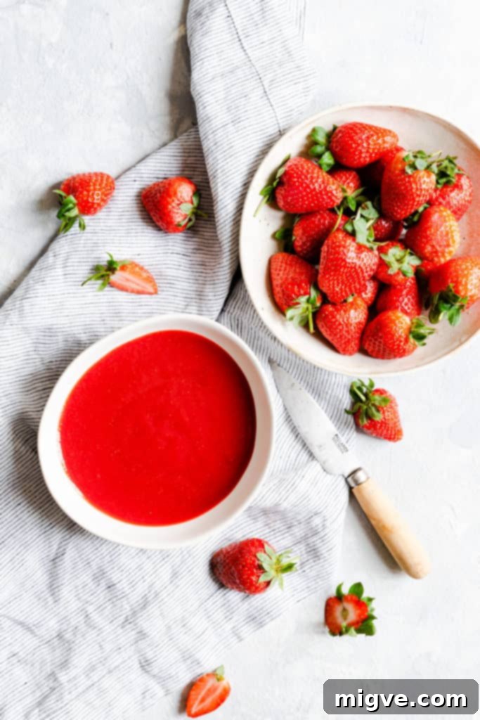 top view of a bowl of strawberry puree and fresh strawberries