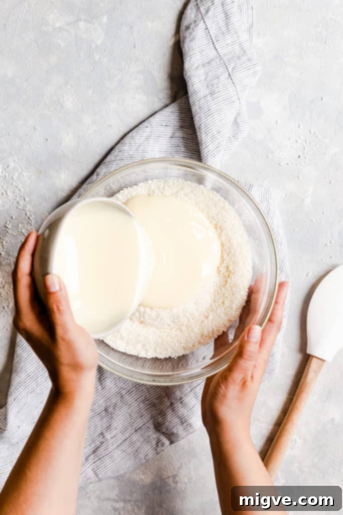 overhead shot of condensed milk being poured into bowl with coconut
