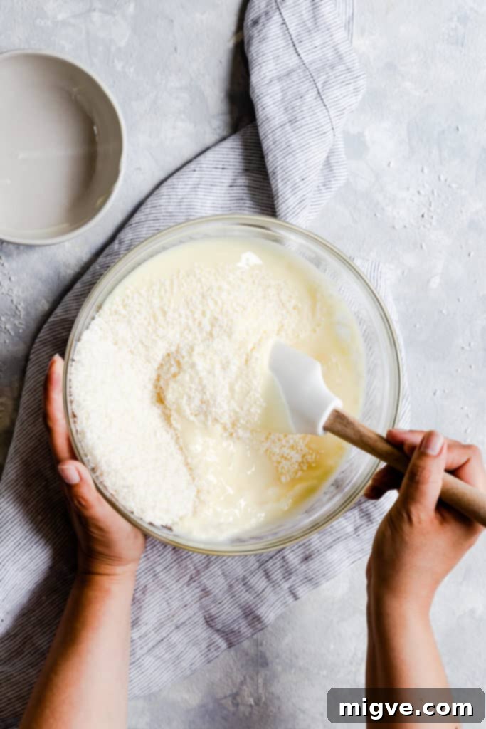 overhead shot of coconut and condensed milk being mixed together in a bowl