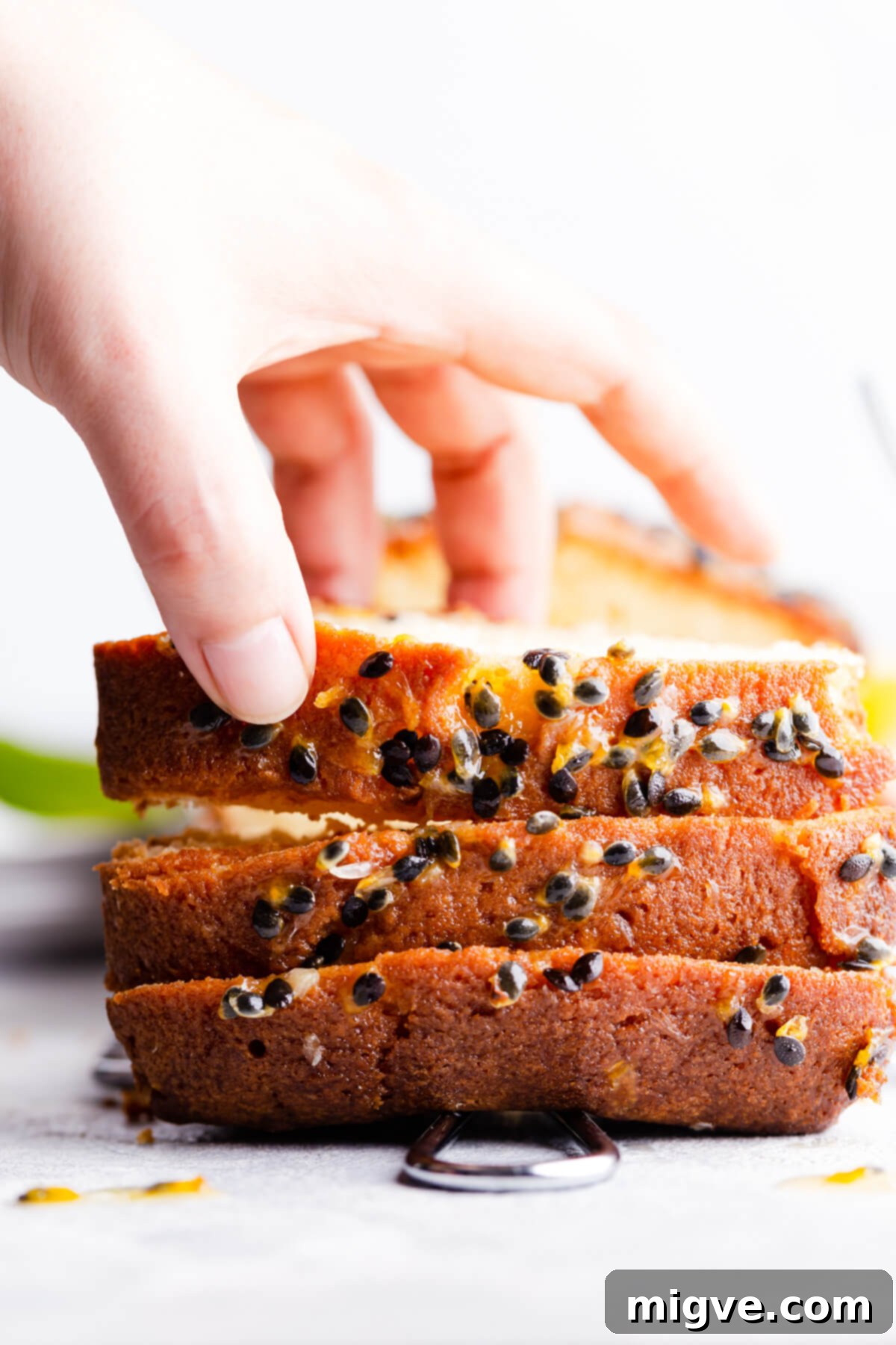 Tropical Passion Fruit Delight 13 A super close-up side view of three slices of passion fruit cake, with one slice being gently lifted, highlighting the moist texture and seeded topping