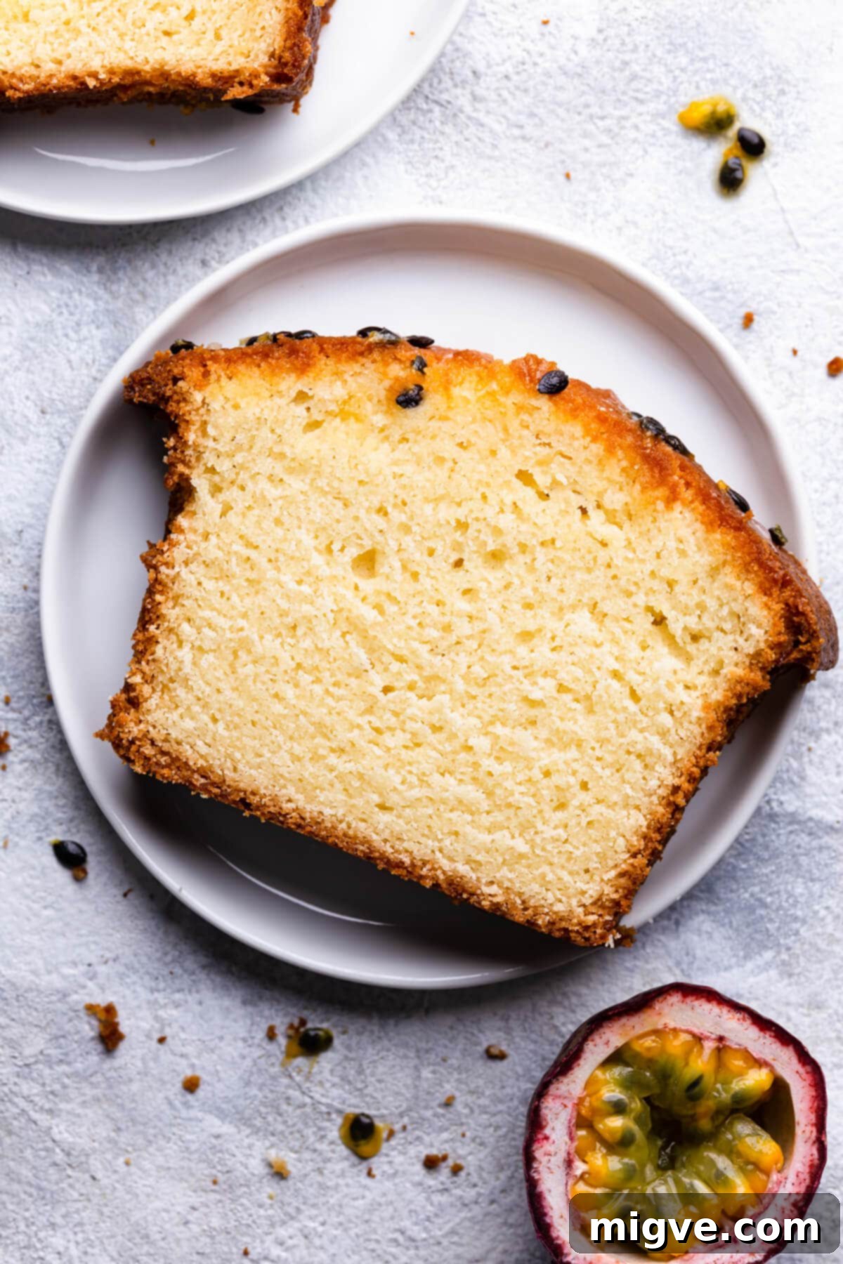 Tropical Passion Fruit Delight 9 Close-up, top view of an individual slice of passion fruit cake on a small white plate, showcasing its moist texture and vibrant seeds
