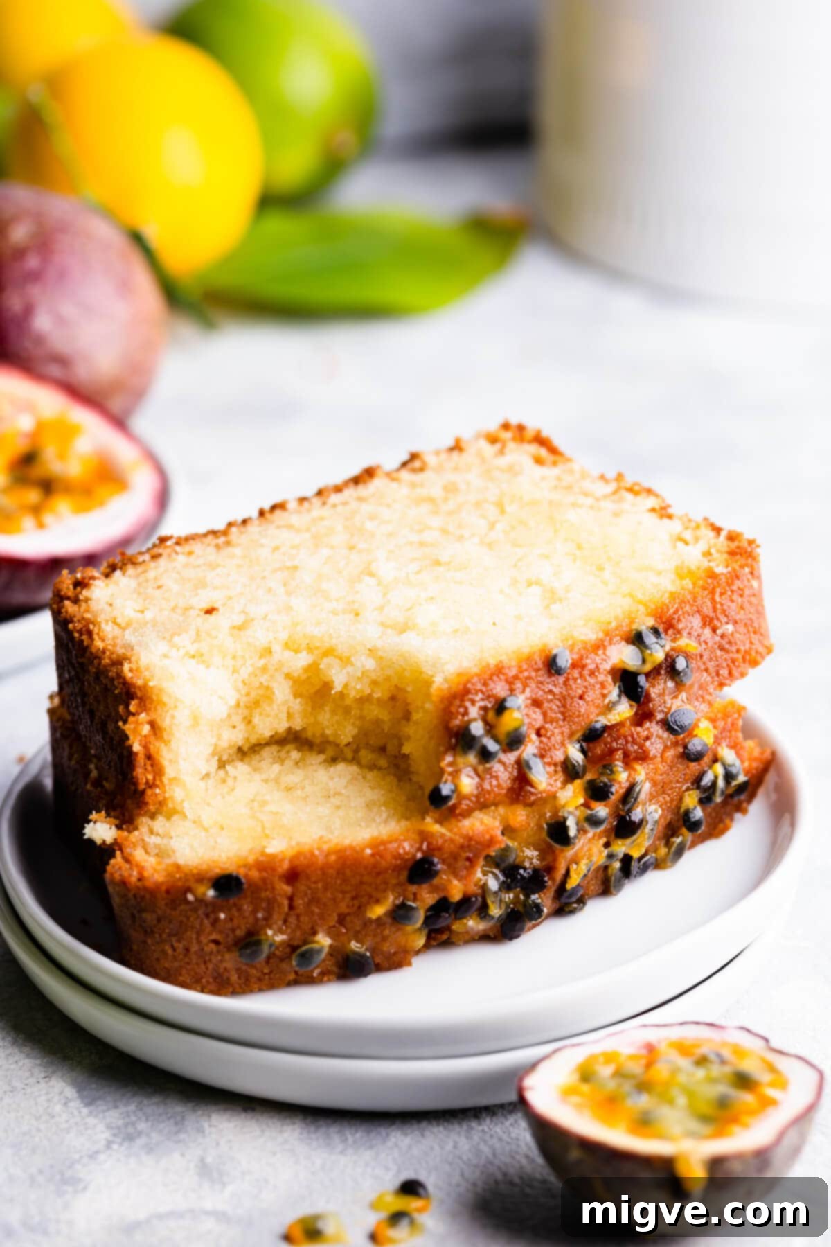 Tropical Passion Fruit Delight 10 Close-up, side view of two slices of passion fruit cake on a small white plate, highlighting the dense, moist crumb and tropical topping