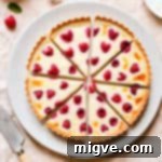 Velvet Raspberry Mascarpone Tart 10 raspberry tart cut into 8 slices and resting on a large plate and pale pink kitchen towel.