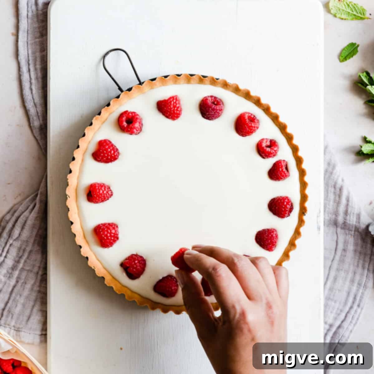 Velvet Raspberry Mascarpone Tart 7 raspberries being arranged on top of the filling for raspberry mascarpone tart.