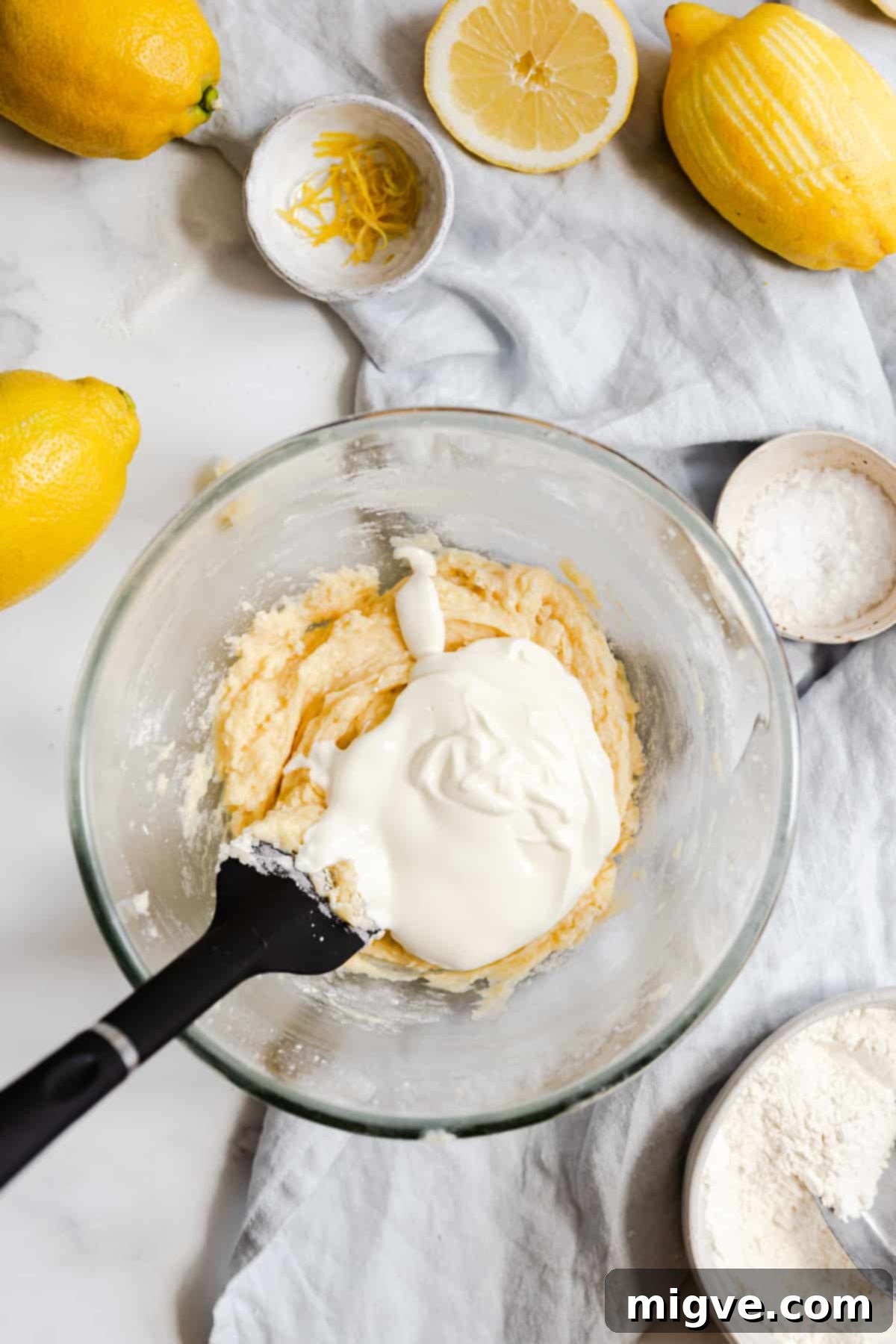 Zesty Small Batch Lemon Drizzle Cake 11 Top view of a mixing bowl showing cake batter with creamy yogurt just added, ready for gentle folding.