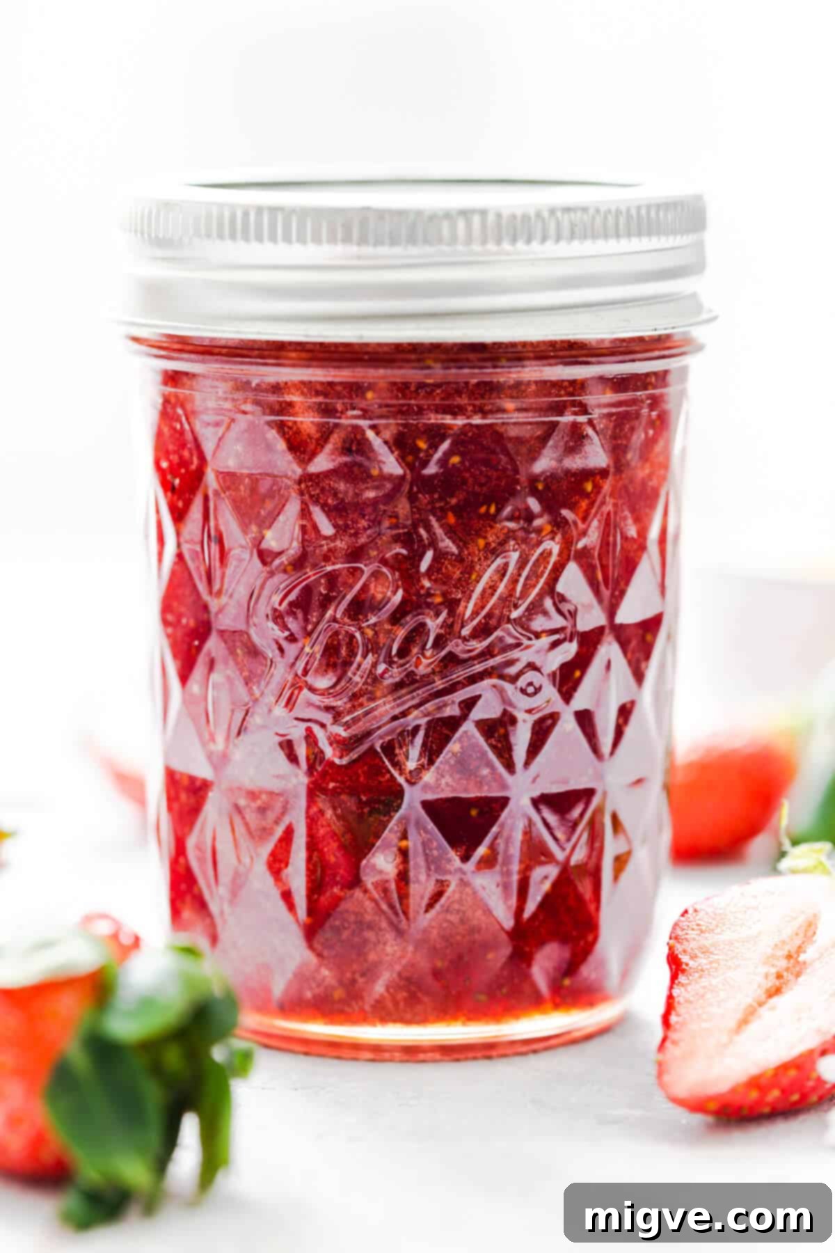 Effortless Strawberry Sunshine 2 straight ahead super close up at a jar of homemade strawberry jam with the lid on