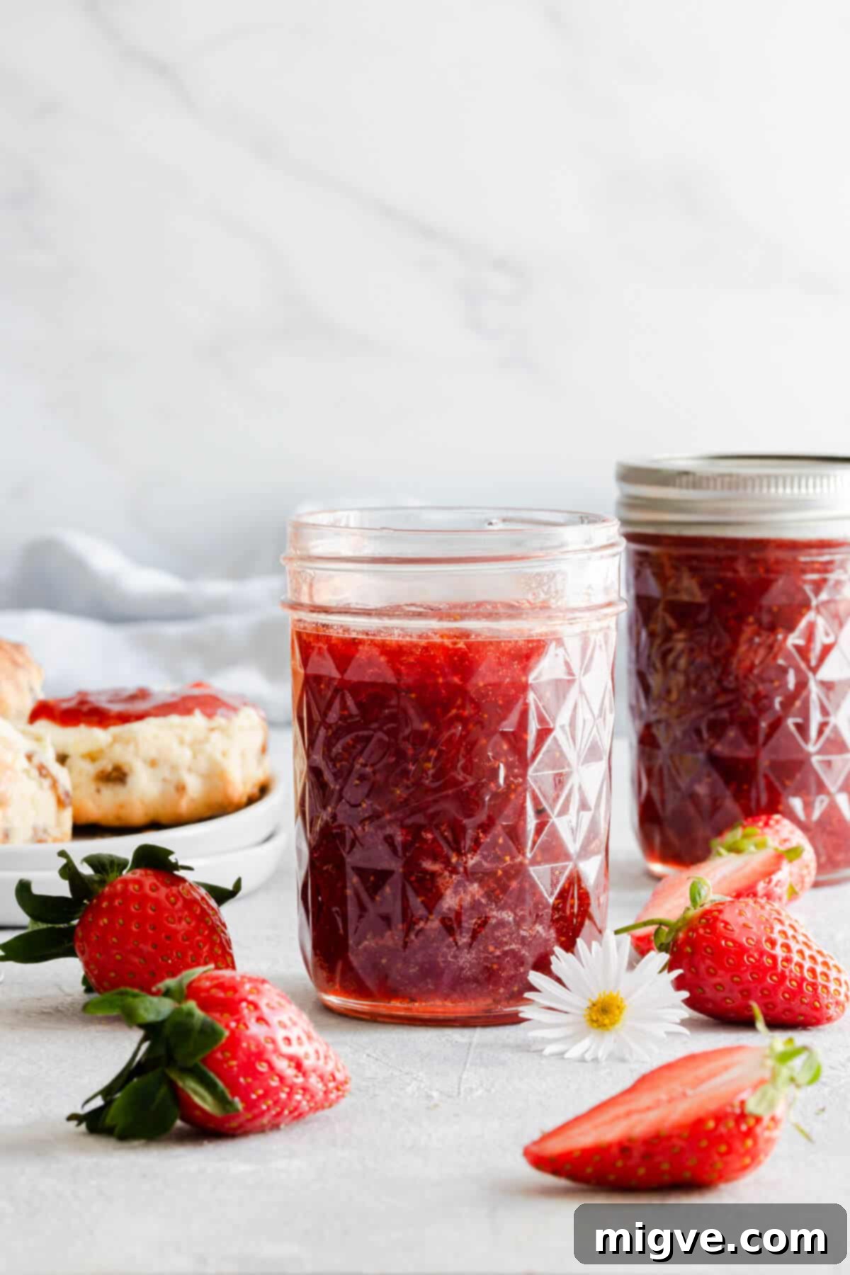 Effortless Strawberry Sunshine 12 straight ahead shot of glass jar with jam inside and fresh strawberries around it