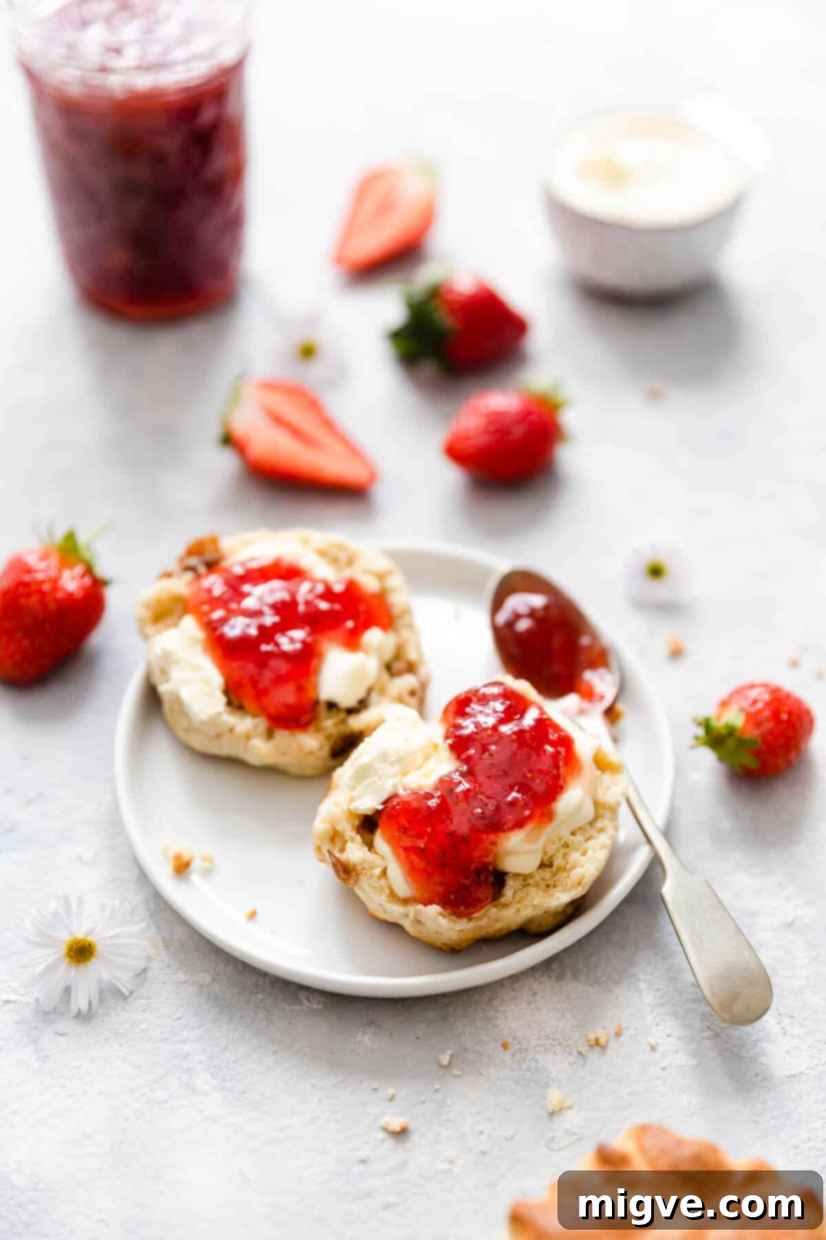 Effortless Strawberry Sunshine 13 top view of scone with cream and jam on a small white plate