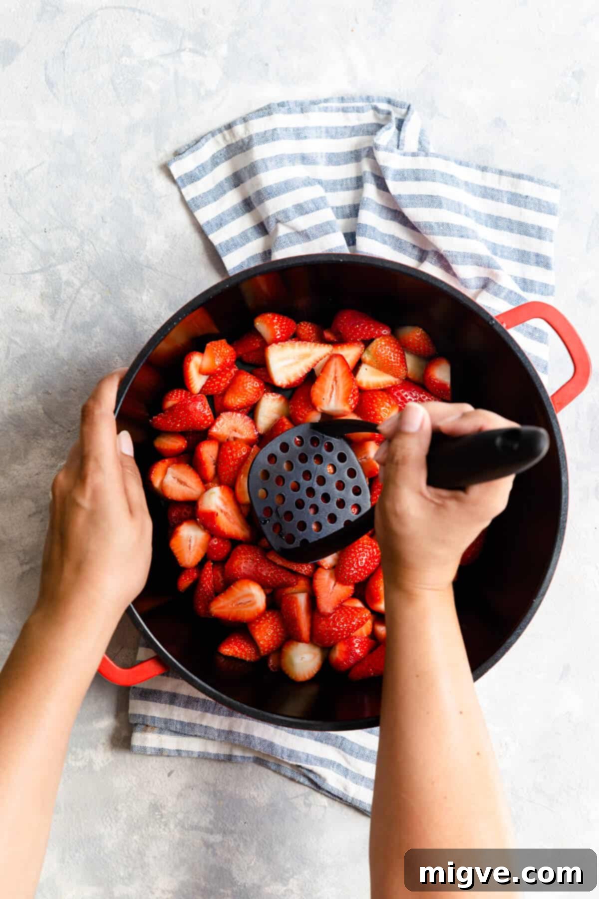 Effortless Strawberry Sunshine 9 top view of a person crushing strawberries with potato masher
