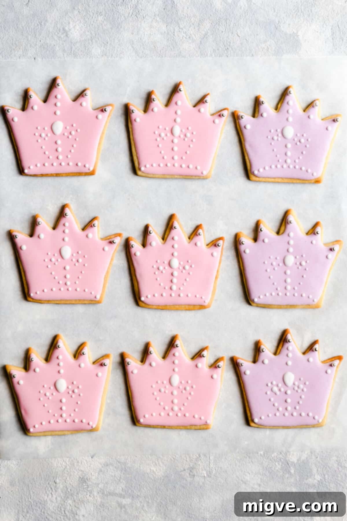 Celebration Sugar Cookie Delights 13 Top-down view of nine perfectly baked and decorated crown-shaped sugar cookies, showcasing their uniform icing and vibrant colors.