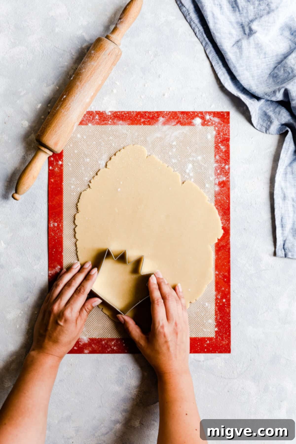 Celebration Sugar Cookie Delights 9 Top-down process shot of a hand using a cookie cutter to shape cookies from the rolled dough.