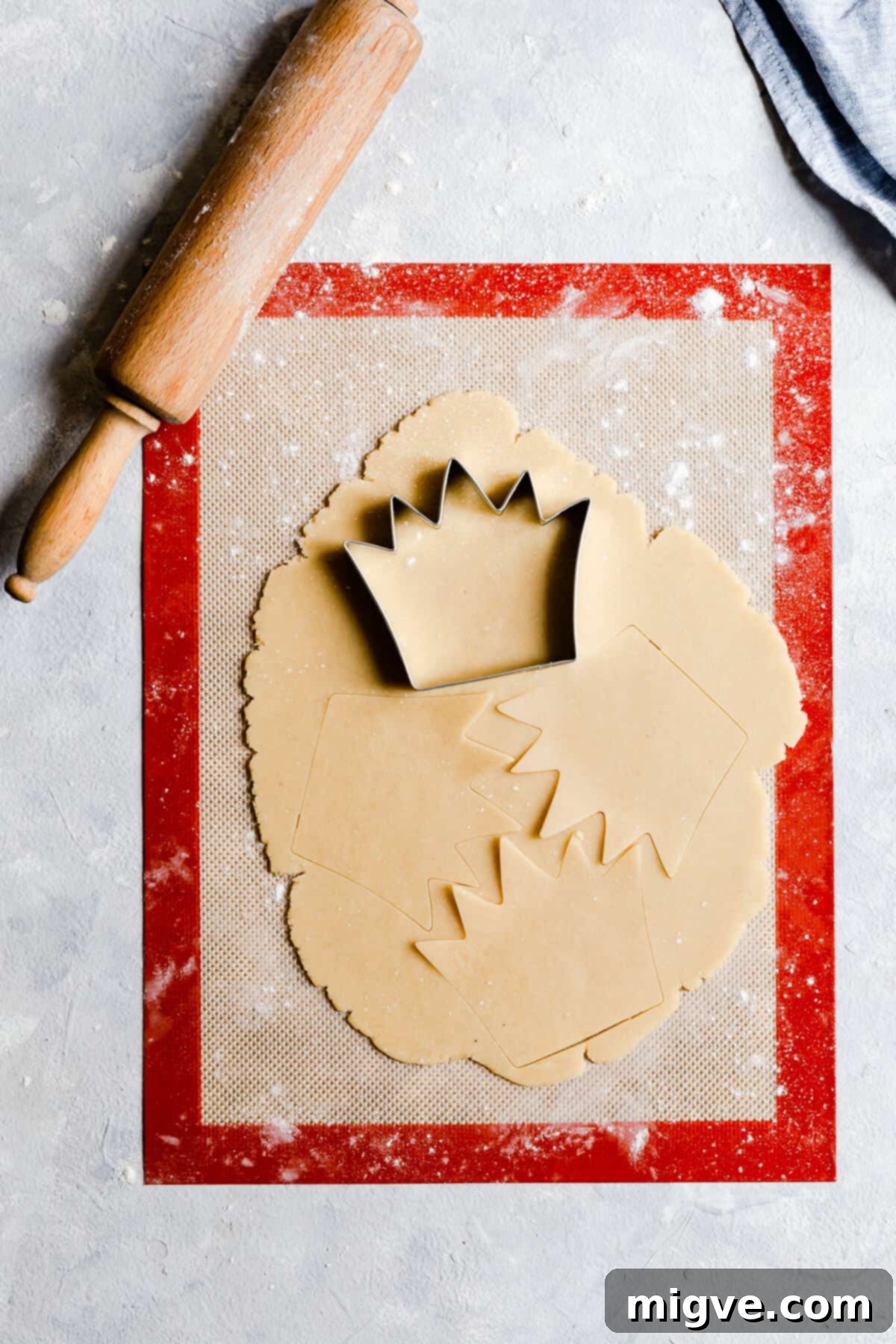 Celebration Sugar Cookie Delights 10 Overhead view of rolled cookie dough with a crown cookie cutter positioned on top, ready for shaping.