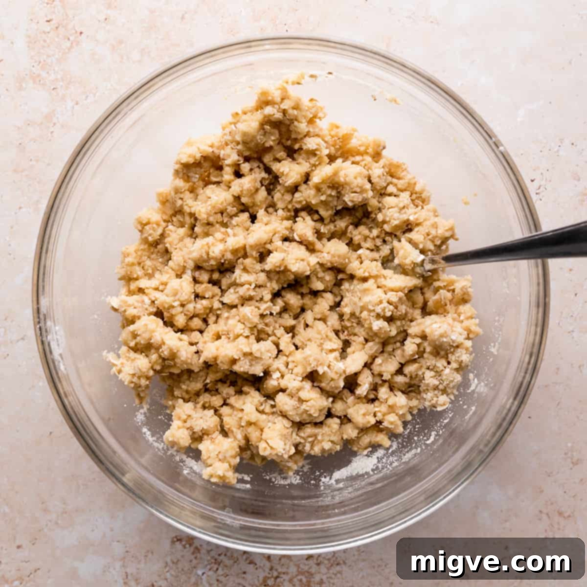A bowl filled with crumble mixture, with a fork resting inside, ready for mixing.