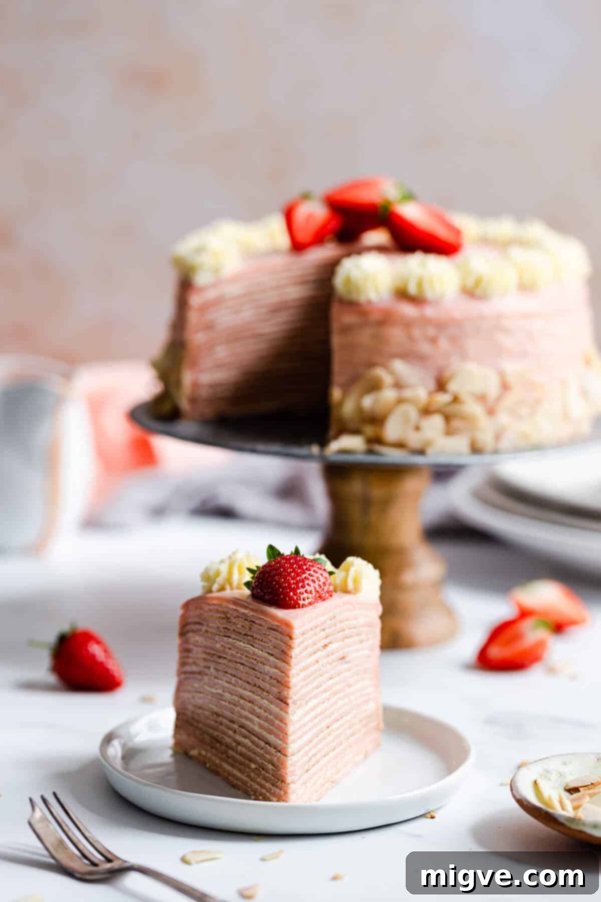 straight ahead shot of a slice of crepe cake on a plate with cake in the background