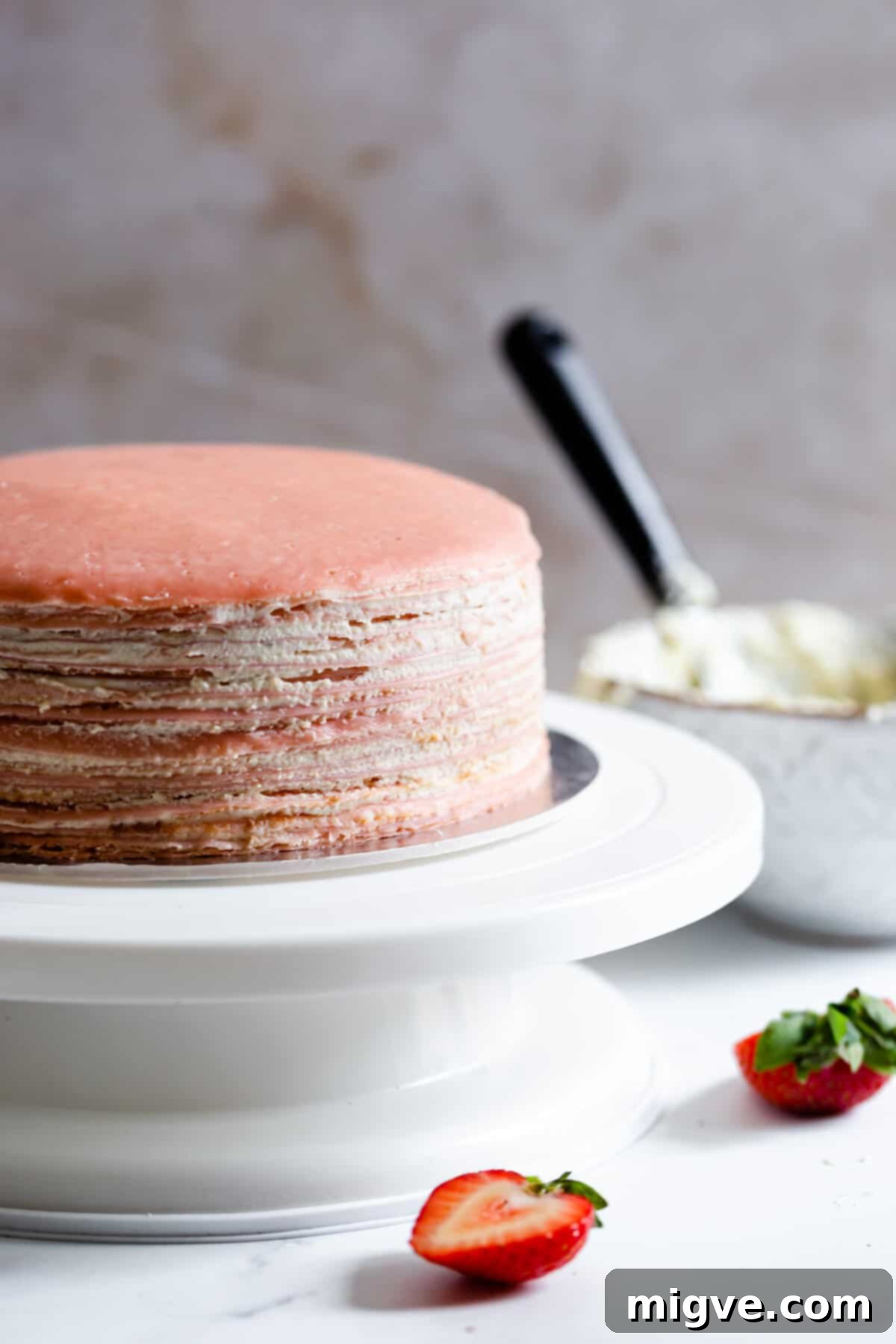side angle super close up showing layers of crepes and whipped cream on cake turning table