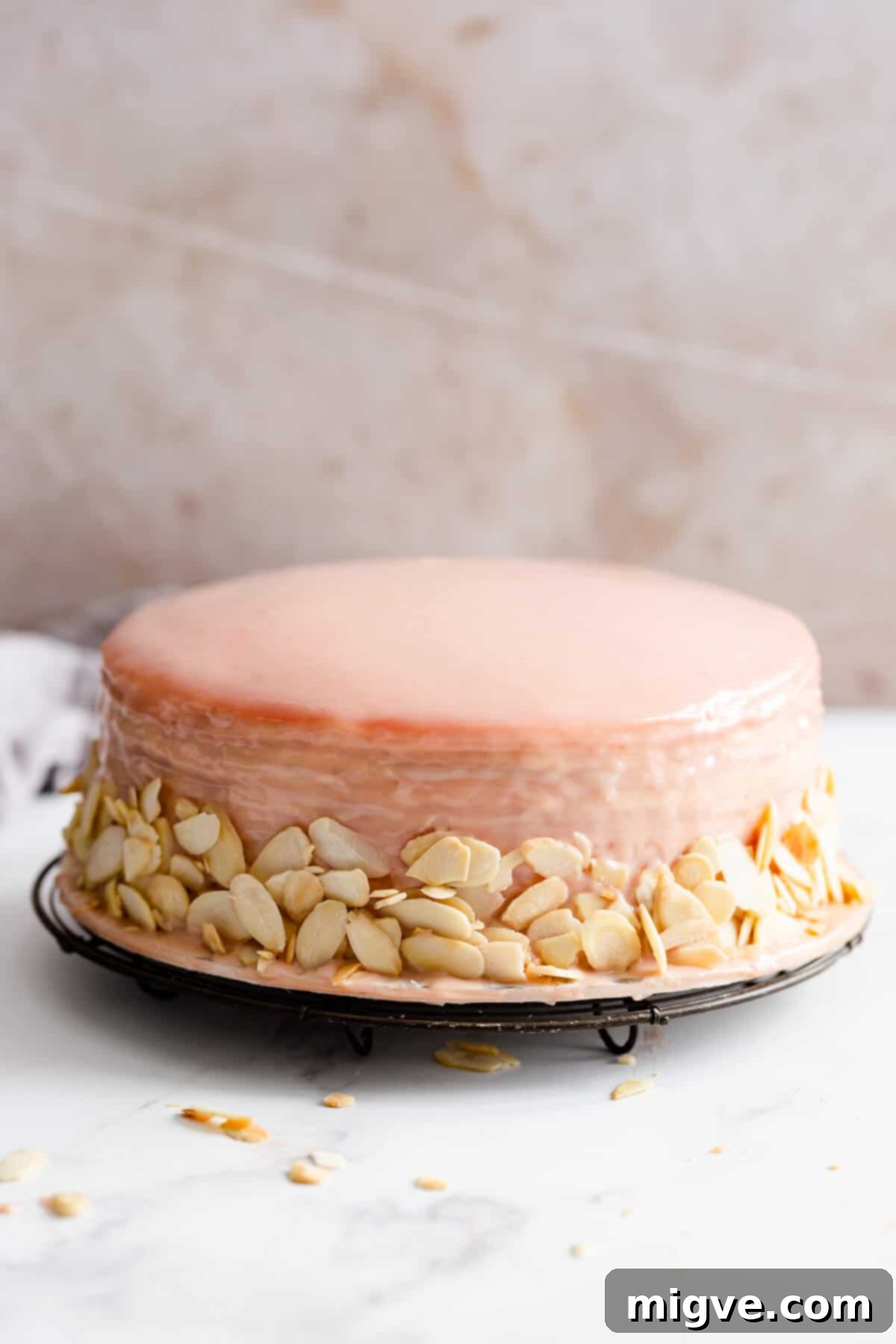straight ahead angle showing crepe cake covered in strawberry ganache and flaked almonds on sides