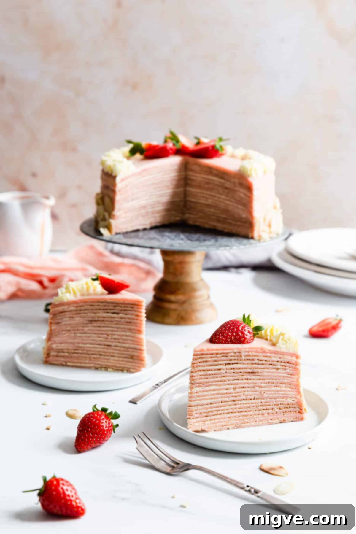 side shot of two individual slices of cake on small plates and cake in the back