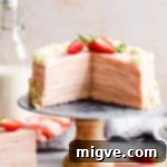 straight ahead shot of a strawberry crepe cake with couple of slices cut out revealing its inside