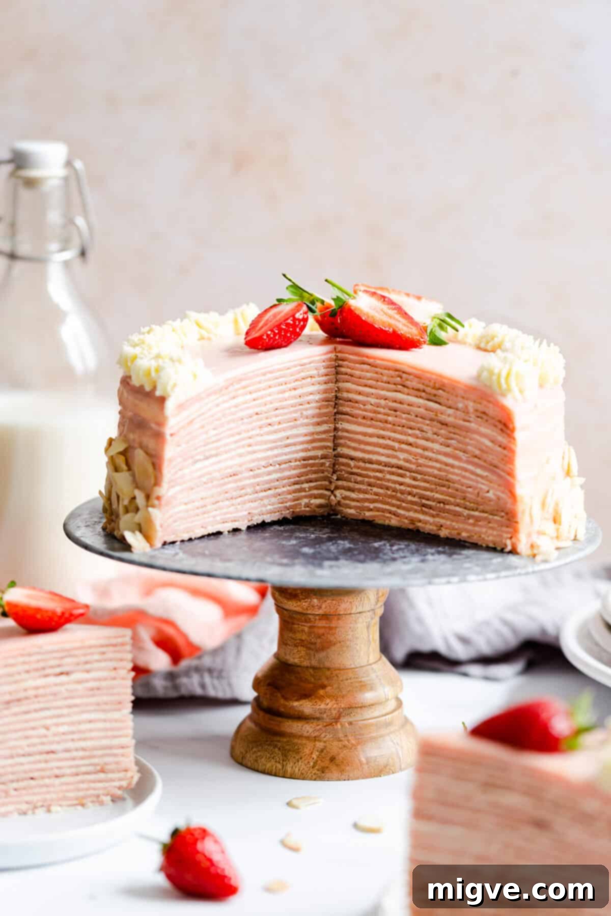straight ahead shot of a strawberry crepe cake with couple of slices cut out revealing its inside