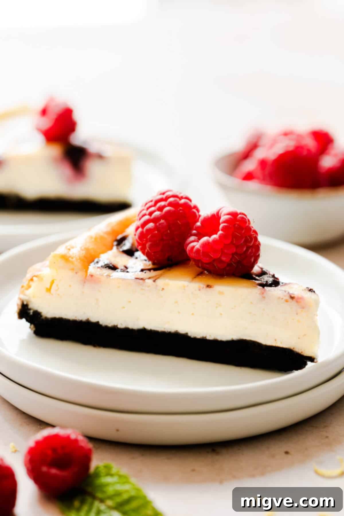 Close-up side view of a generous slice of raspberry ripple cheesecake on a small plate, showcasing its layers and vibrant ripple.
