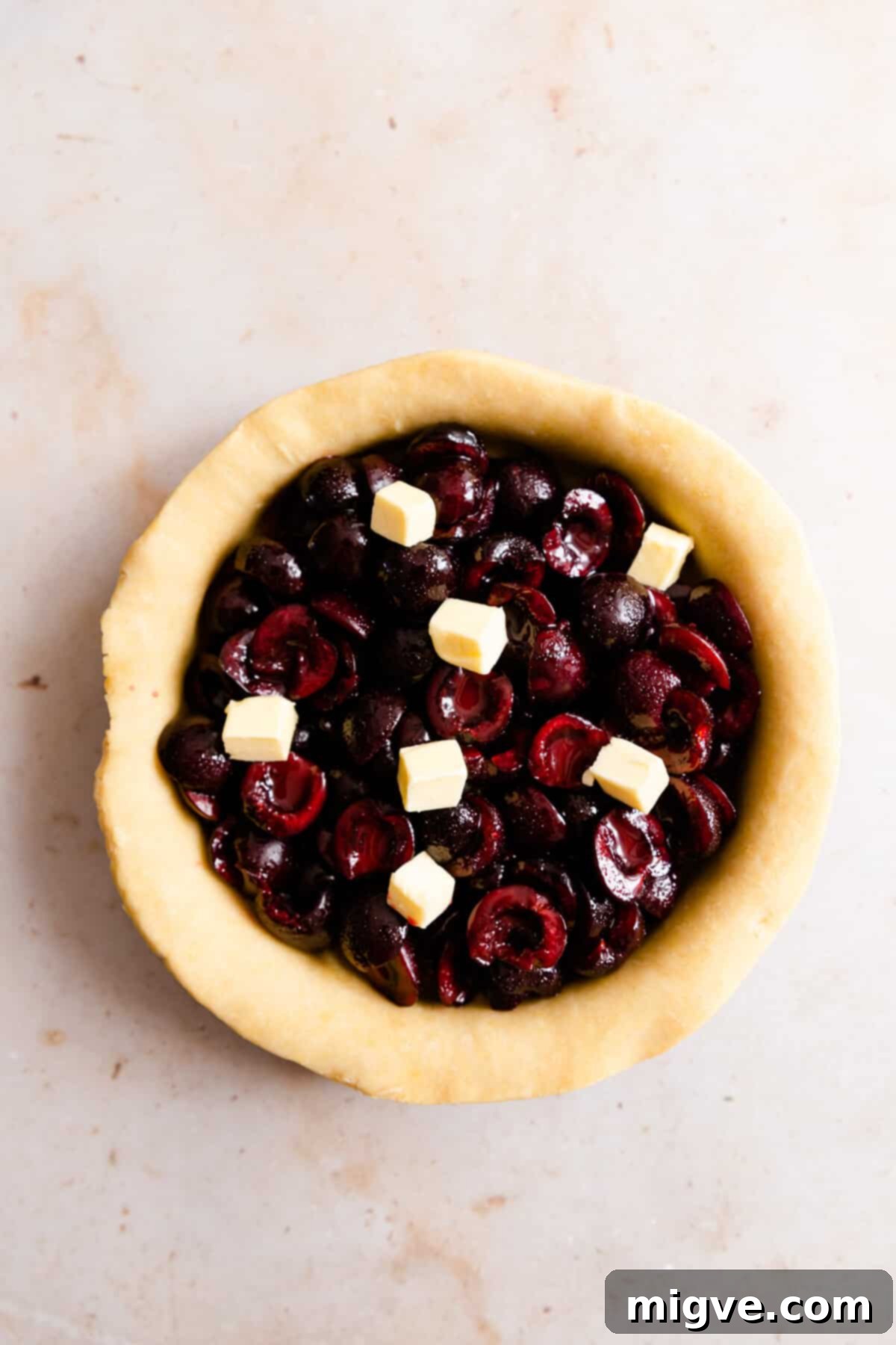 overhead shot showing cherry filling in a pie dish with small cubes of butter on top