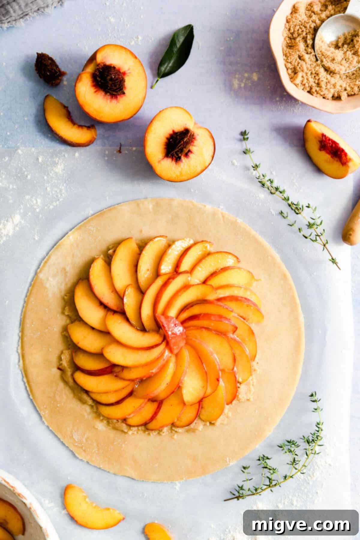 top view of a large circular galette dough topped with an abundance of vibrant sliced peaches