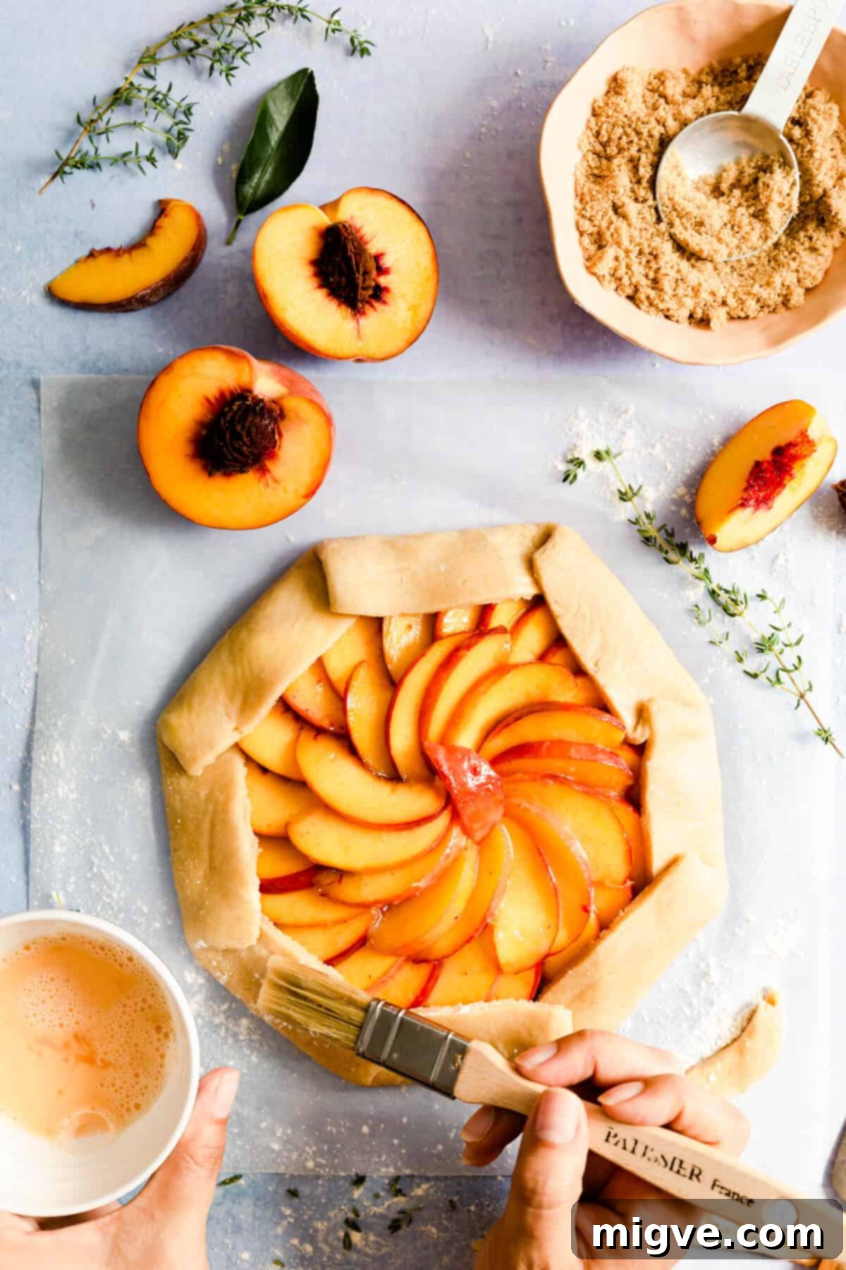 overhead shot of brown sugar peach galette being brushed with egg wash before baking
