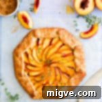 top view of baked peach galette with fresh thyme sprinkled on top