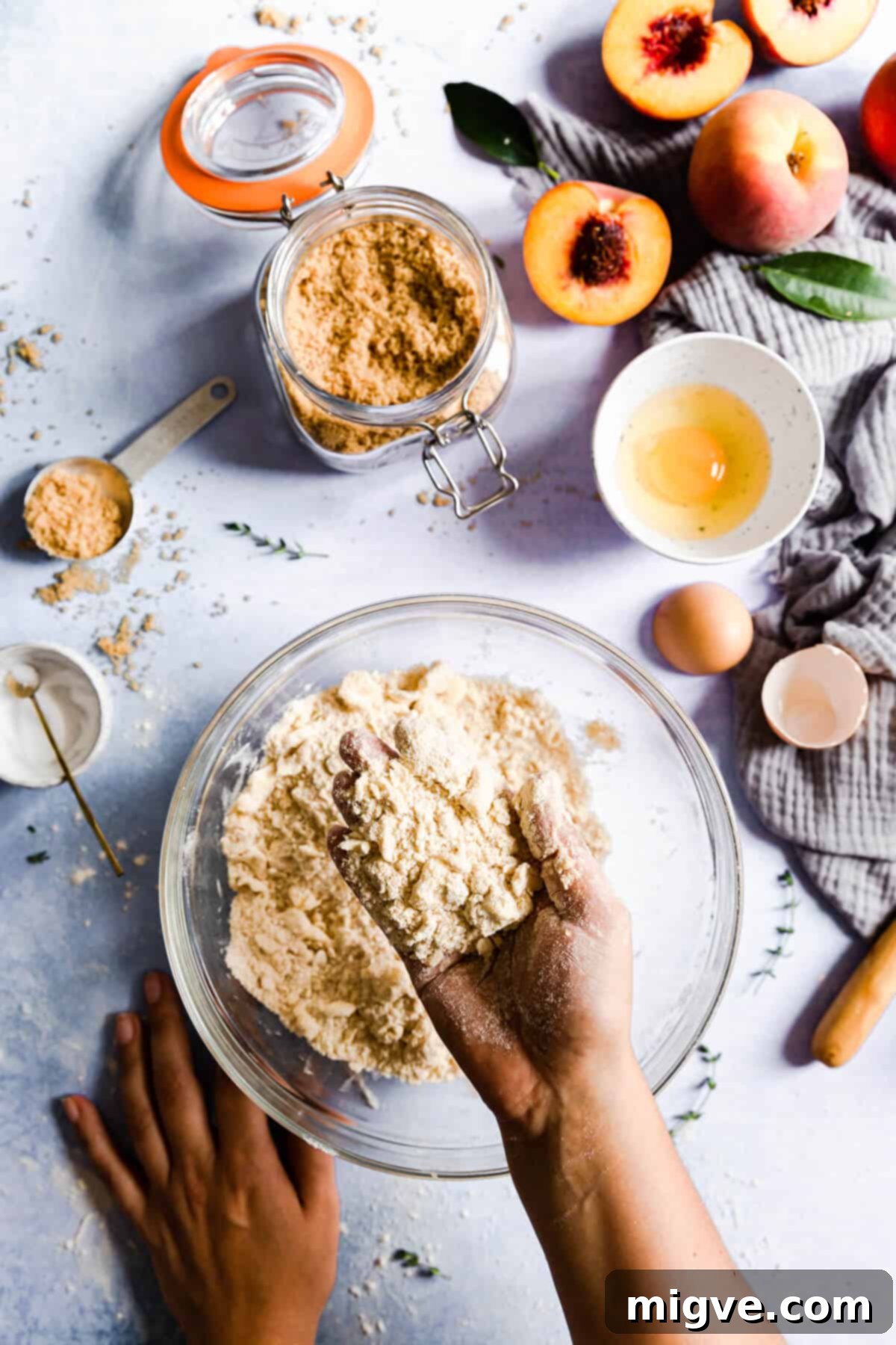 top view of hands working flour and butter mixture, forming a coarse, crumbly dough