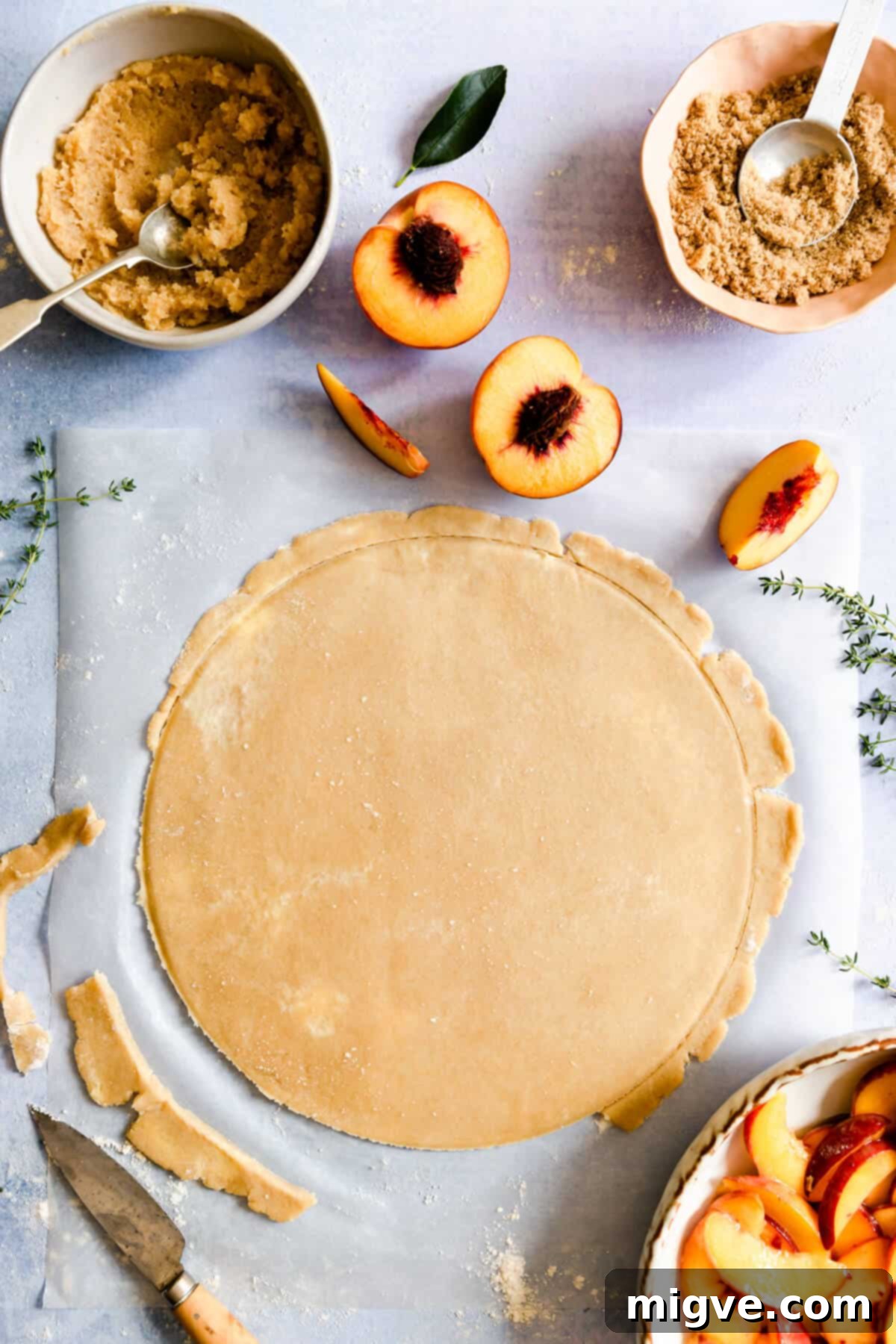 top view of peach galette crust rolled into a large, even circle on parchment paper