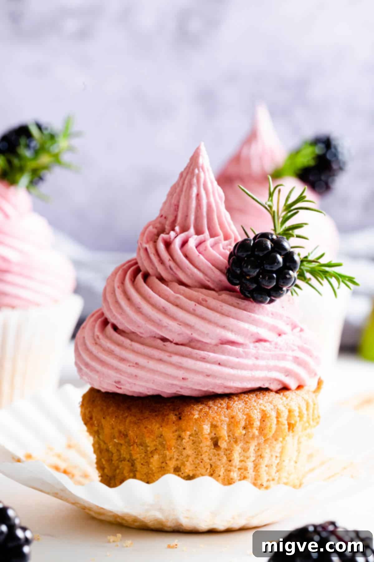 Super close-up shot of a single spiced apple cupcake with smooth pink blackberry buttercream, presented elegantly in a paper case.