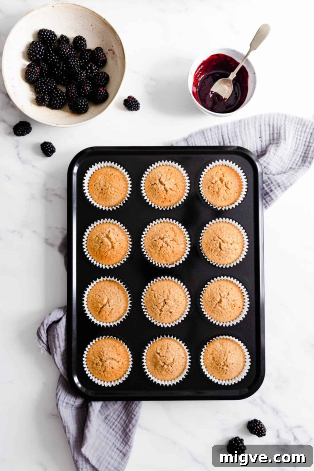 Top view of a baking tray filled with spiced apple cupcakes, freshly baked and golden brown, cooling down after coming out of the oven.