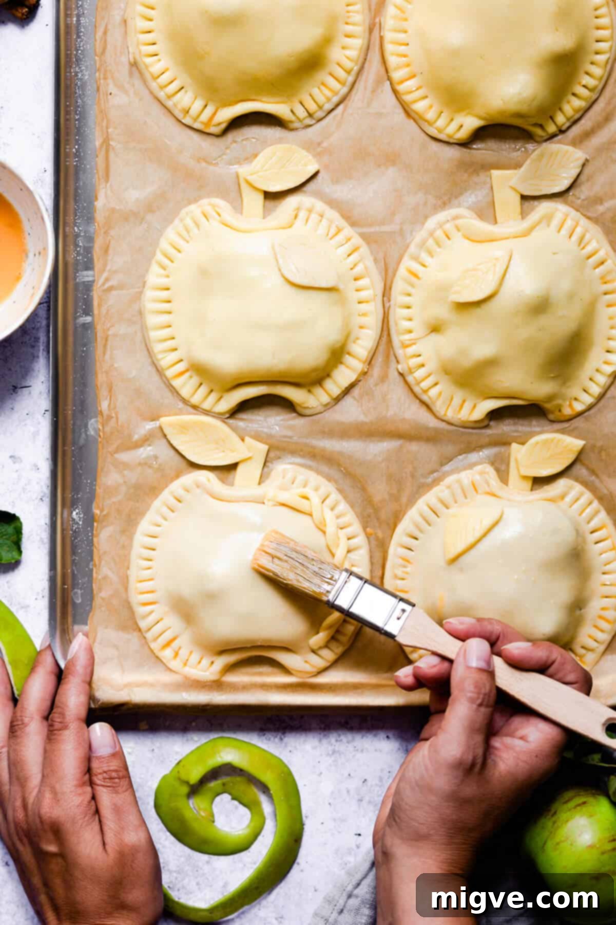 top view of a person brushing some egg wash on top of hand pies