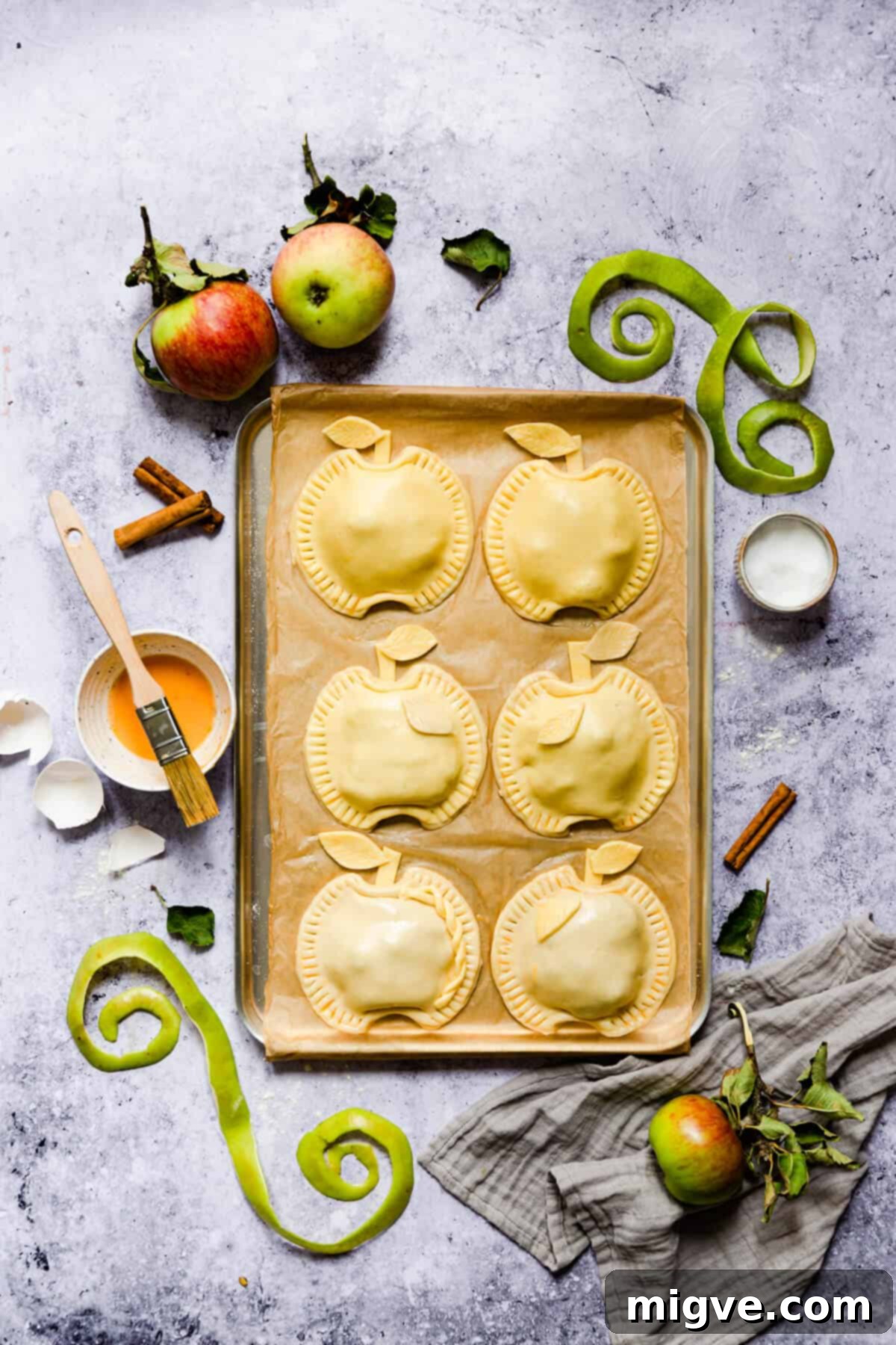 overhead shot of hand pies shaped into apples on a baking tray