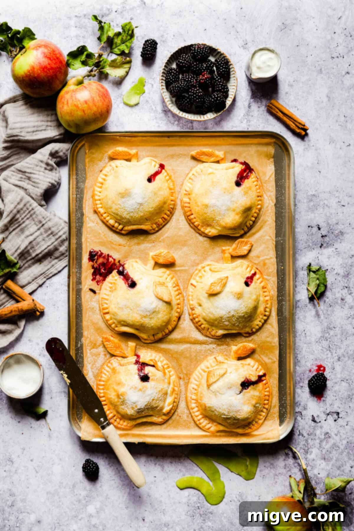 overhead shot of baked apple and blackberry hand pies on a baking tray