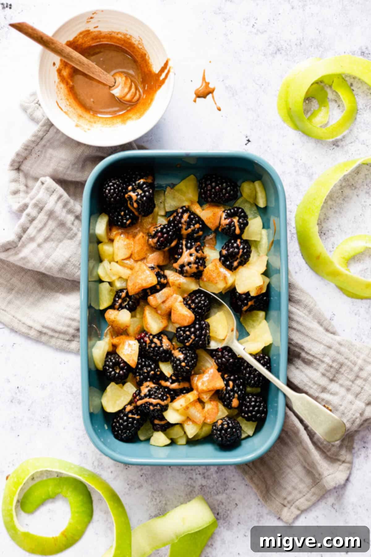 top view of a small dish with cooked apple chunks and some blackberries drizzled with glaze
