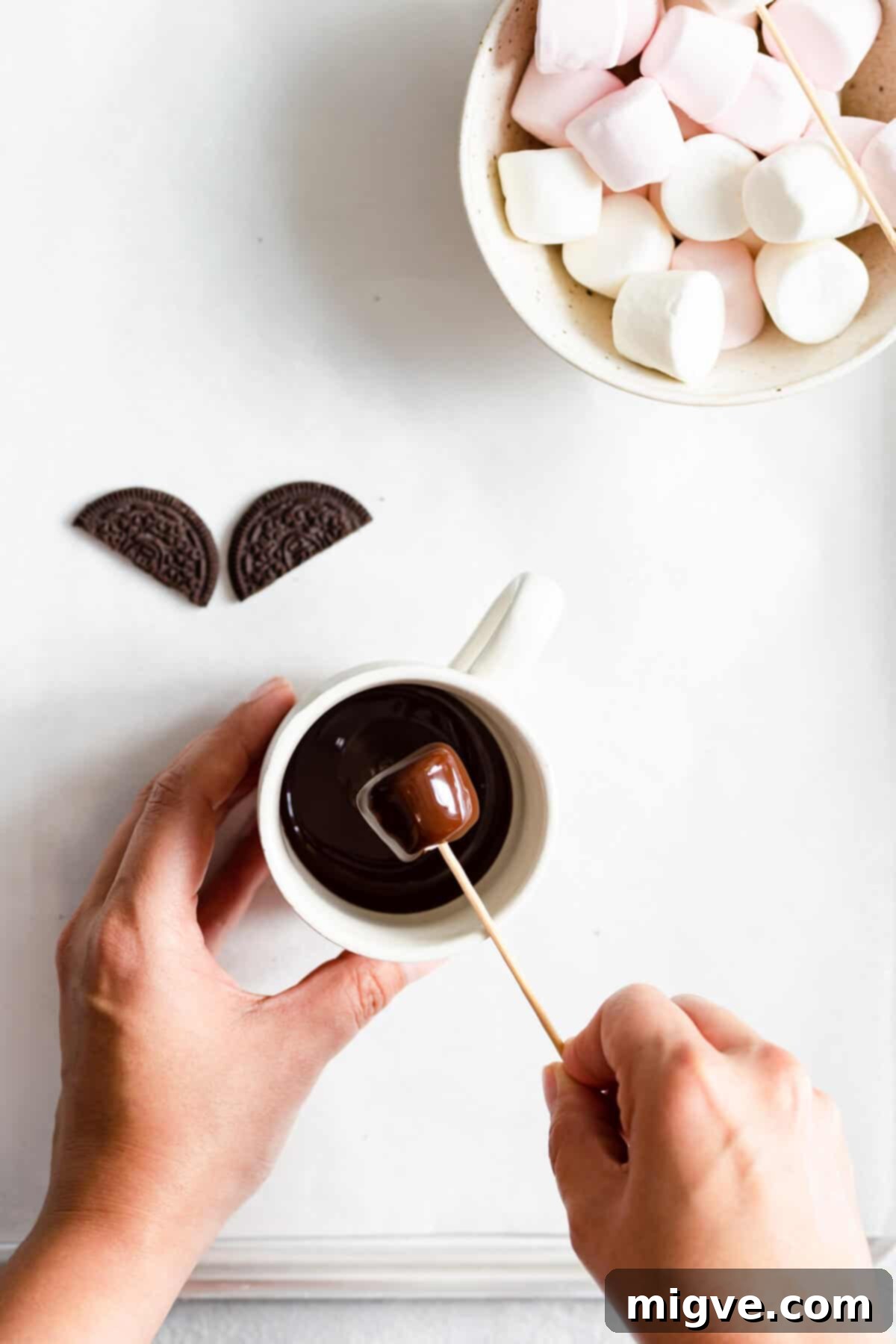 Midnight Marshmallow Bats 6 overhead shot of a person dipping a marshmallow into melted chocolate