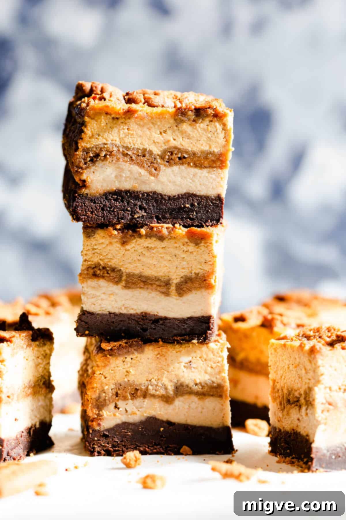 side angle shot of three slices of pumpkin biscoff cheesecake brownie bars stacked on top of each other
