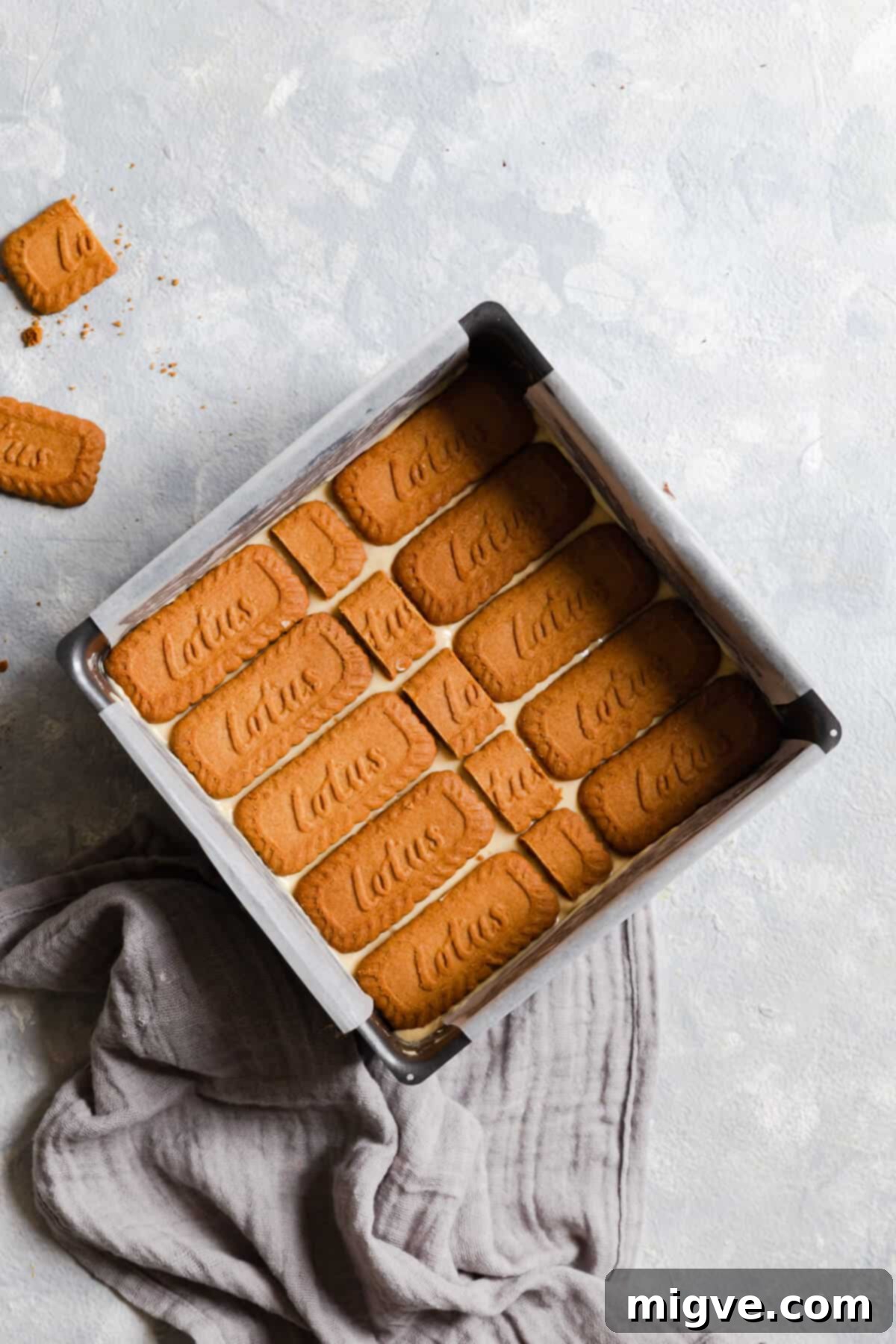 top view of a baking tin with cake batter topped with Lotus biscuits